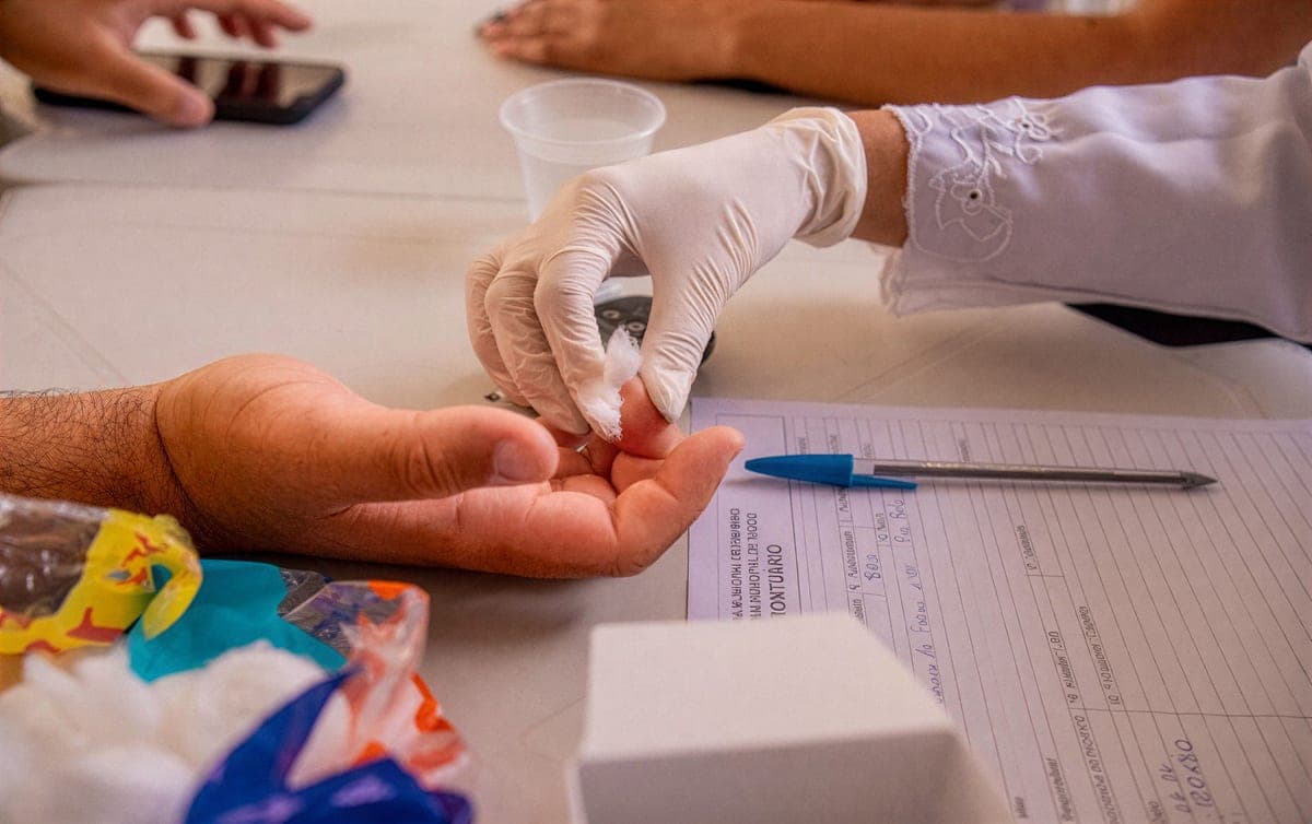 Profissional de saúde realizando teste rápido em mesa de atendimento comunitário